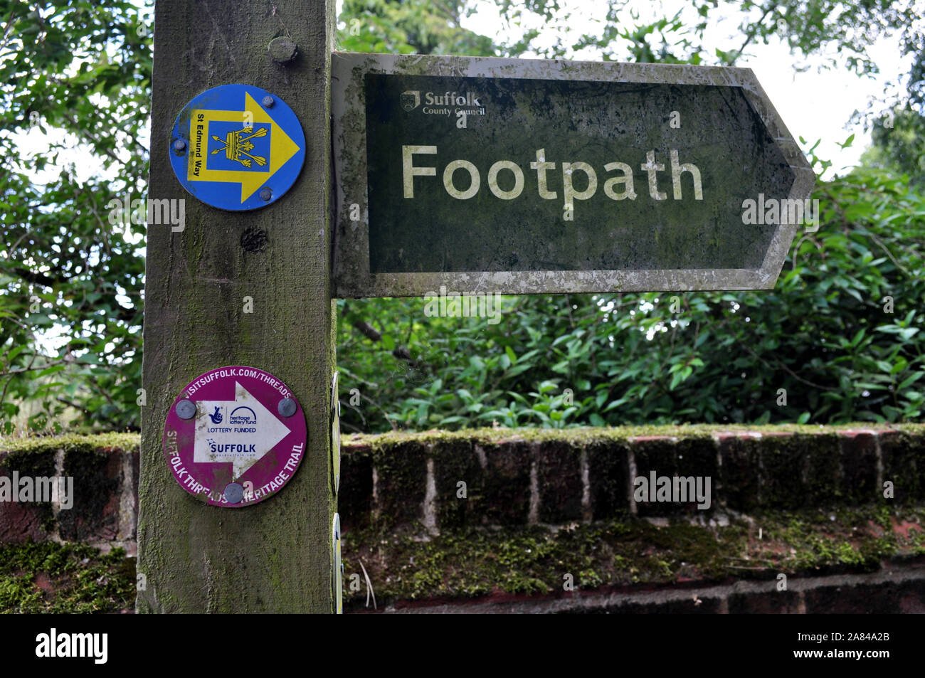 Directional signage for Suffolk Coastal footpath and St Edmunds Way with green algae growth located near Lavenham UK Stock Photo