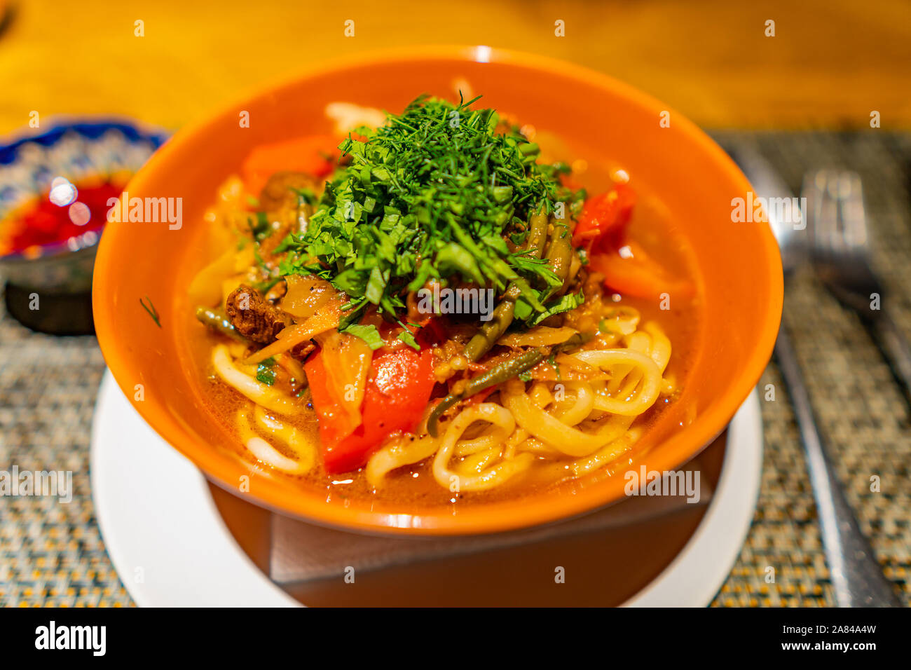 Traditional Kazakhstan Mouthwatering Lagman with Lamb Meat and Vegetables Served in a Orange Colored Bowl Stock Photo