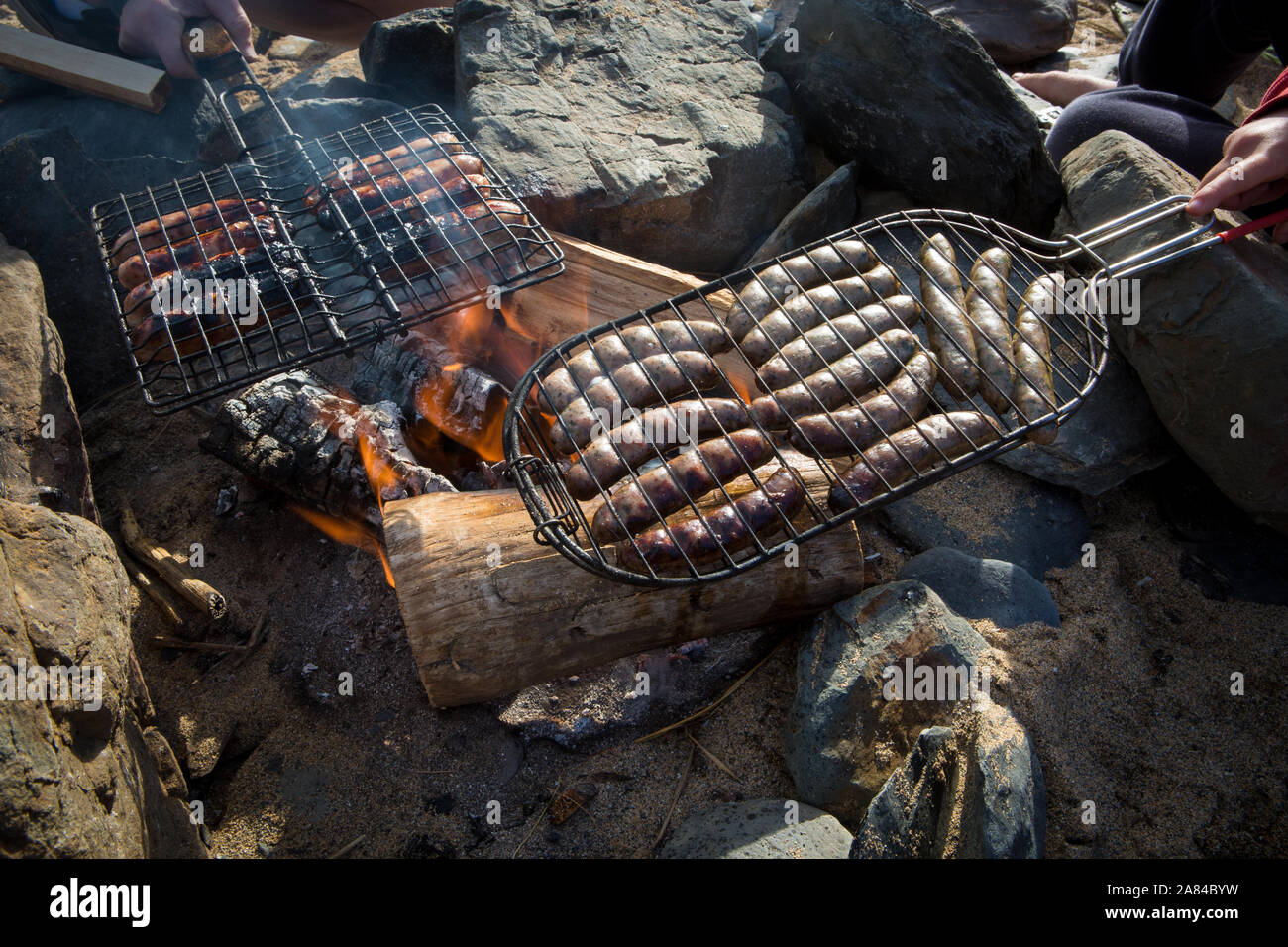 BBQing sausages on an open fire on the beach, Cornwall, England. Stock Photo