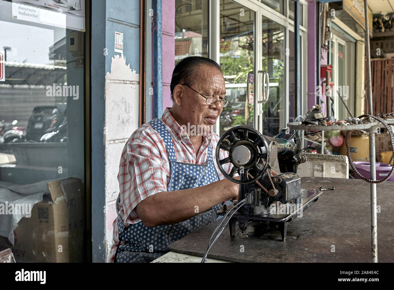 Repair man servicing vintage Singer sewing machine. Thailand Southeast Asia Stock Photo