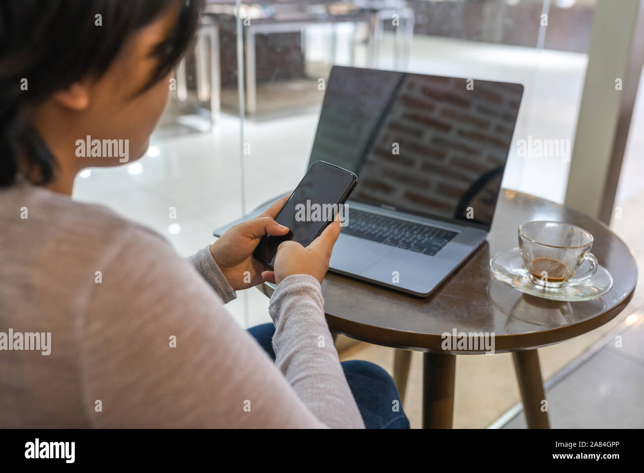 Woman working on laptop and using cellphone at coffee table Stock Photo