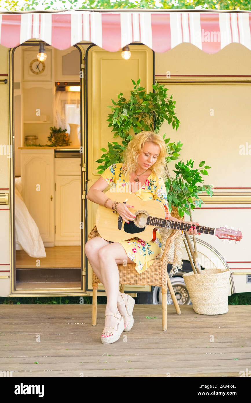 Loving middle age girlfriend with long blonde hair plays the guitar and  singing song near camper van trailer Stock Photo - Alamy