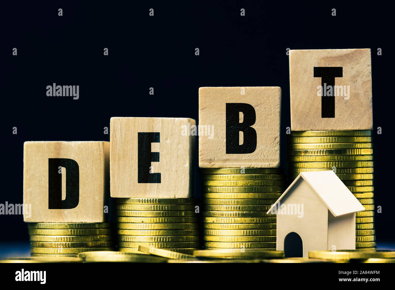 Conceptual about property debt. A small house model with rising stack of coins on dark background. Depicts debt resulting from the purchase of an expe Stock Photo