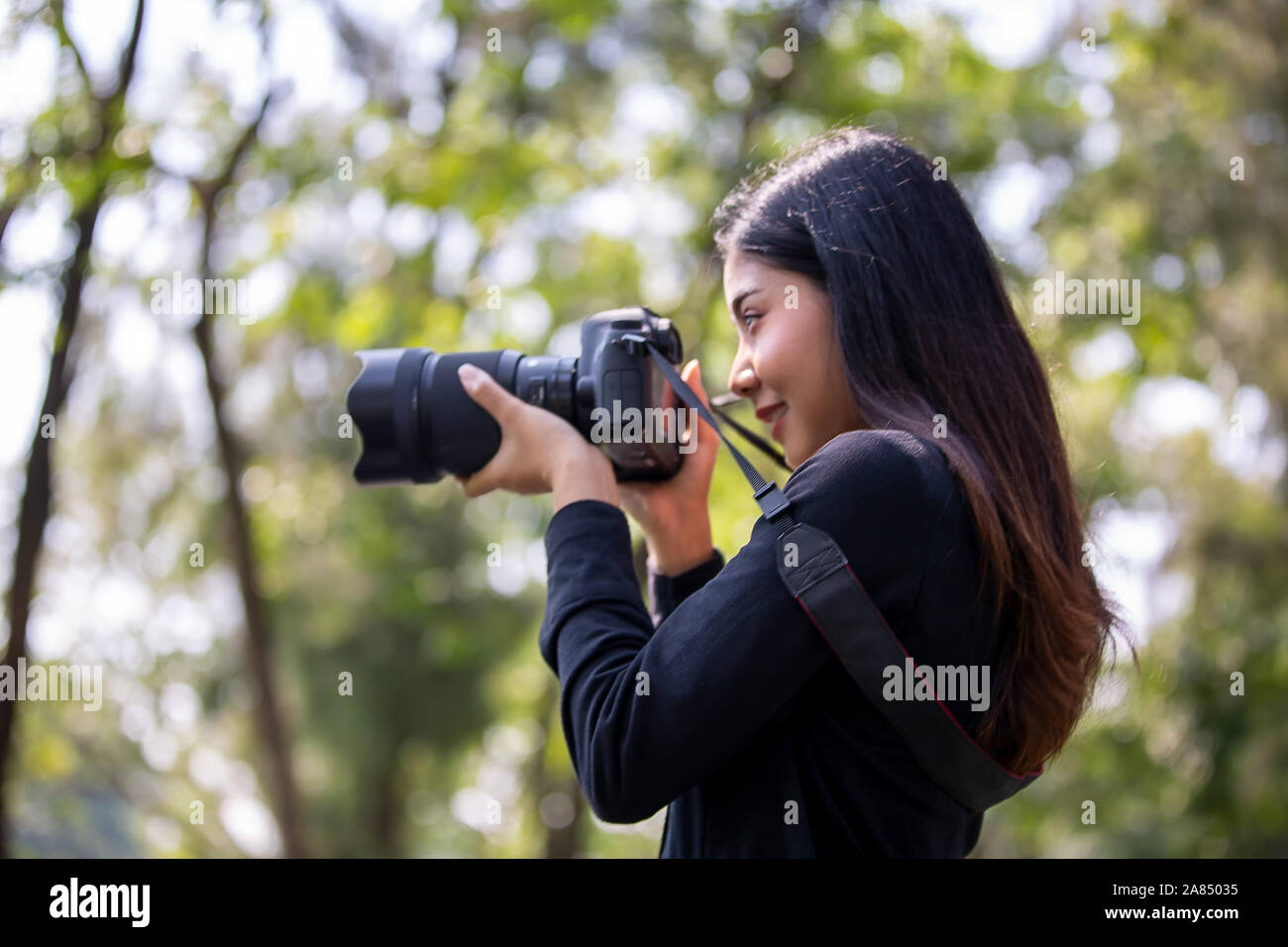 young woman holding camera and shooting photo in the park Stock Photo ...