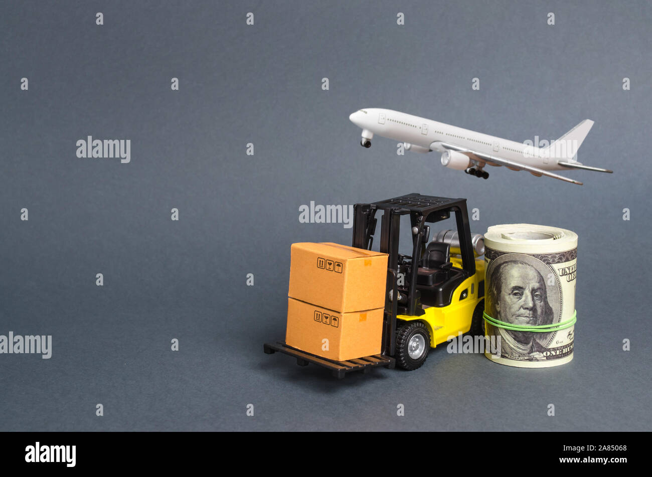 A forklift truck carries cardboard boxes near a dollar roll and airplane. Transport company. Performance efficient. Trade and production of products a Stock Photo