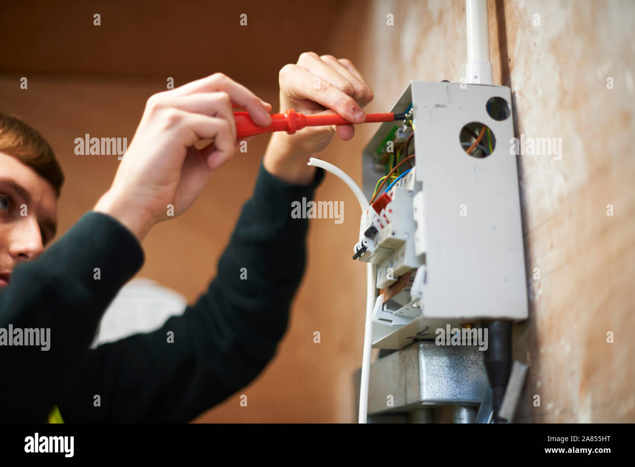 Male electrician using screwdriver, working at electric panel Stock Photo