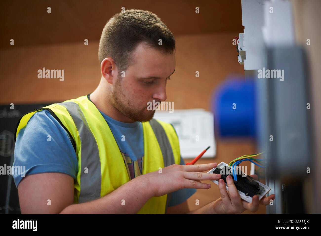 Male electrician student examining light switch in workshop Stock Photo