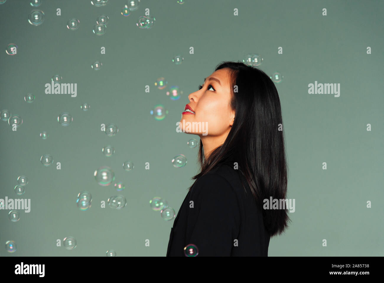 Curious, imaginative young woman watching falling bubbles Stock Photo
