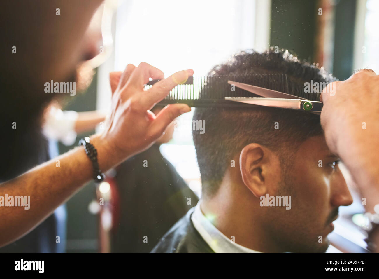 Male barber giving customer a haircut in barbershop Stock Photo