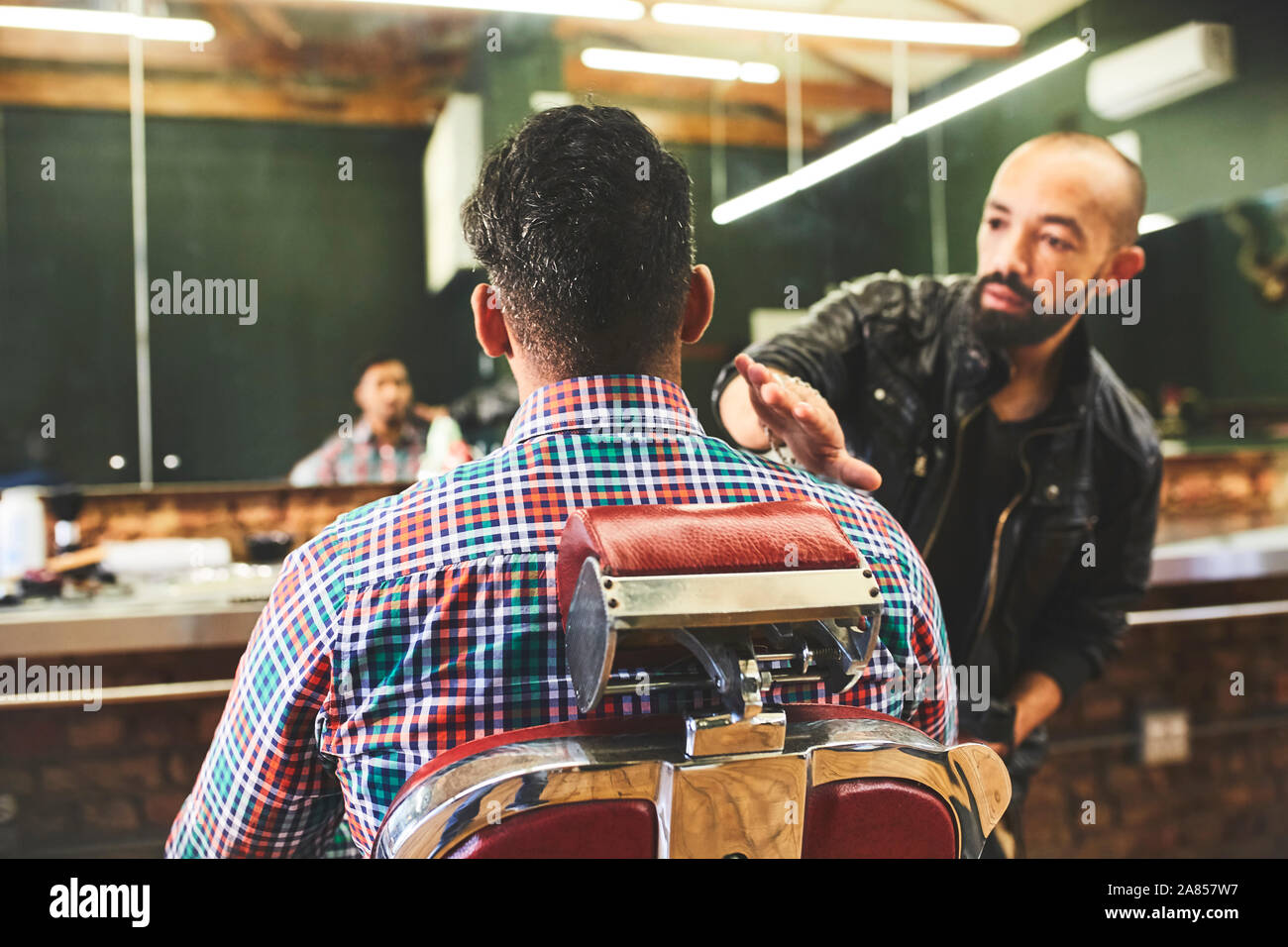 Male barber checking haircut of customer in barbershop Stock Photo