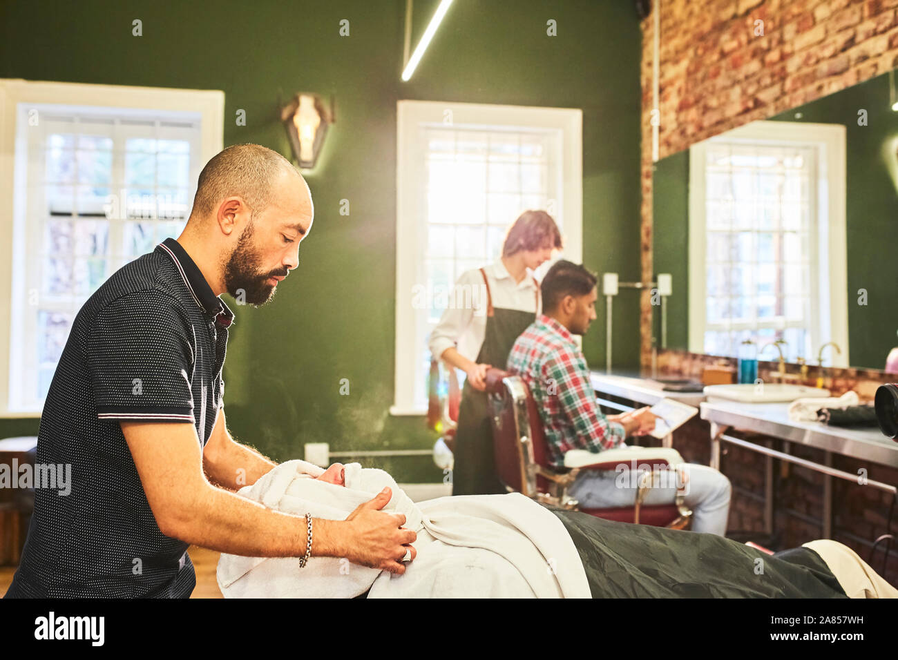 Male barber steaming face of customer in barbershop Stock Photo