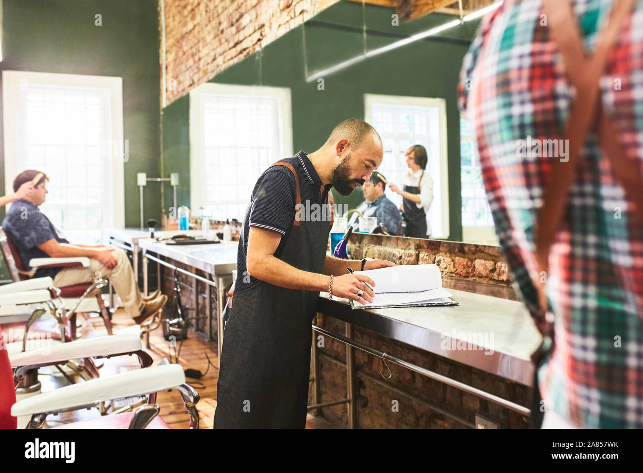Male barber looking at schedule in barbershop Stock Photo