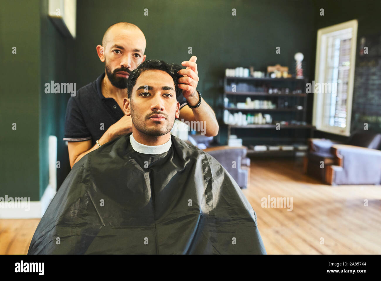 Male barber giving customer haircut in barbershop Stock Photo