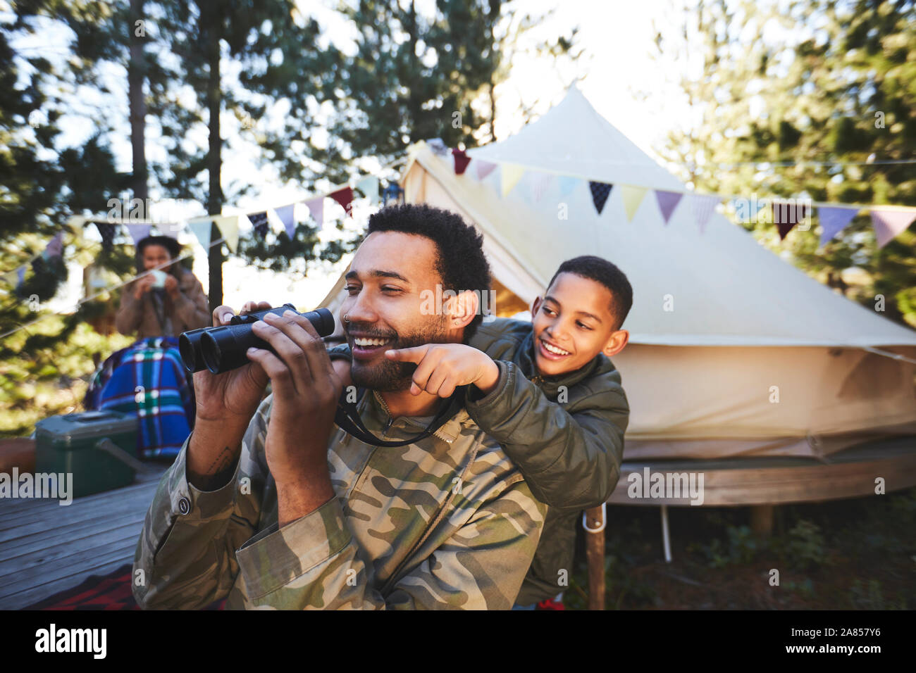 Happy, curious father and son with binoculars at campsite Stock Photo