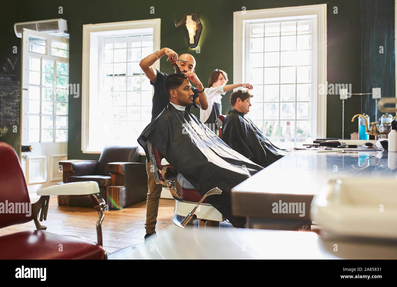 Male barber cutting hair of customer in barbershop Stock Photo