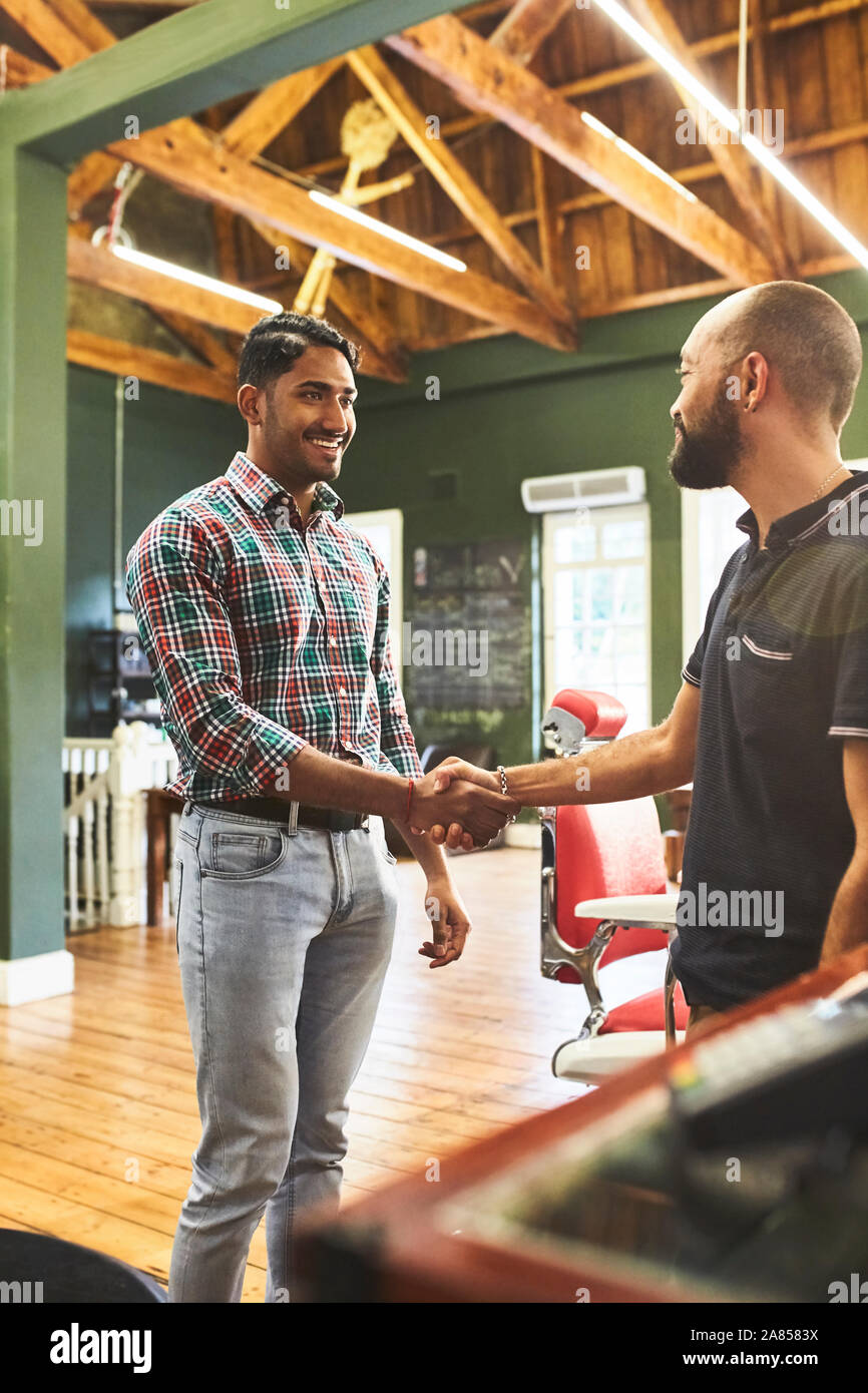 Male barber and customer shaking hands in barbershop Stock Photo