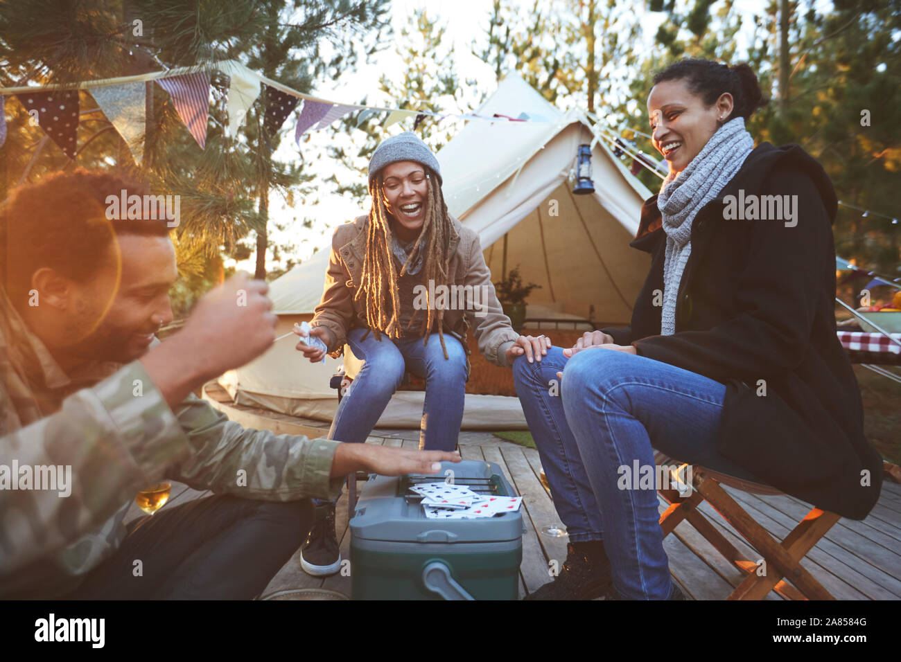 Happy friends playing cards at campsite Stock Photo