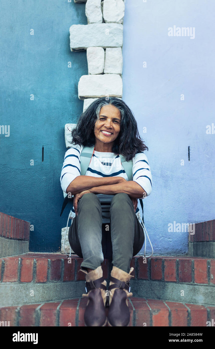 Portrait smiling, confident woman sitting on brick steps Stock Photo