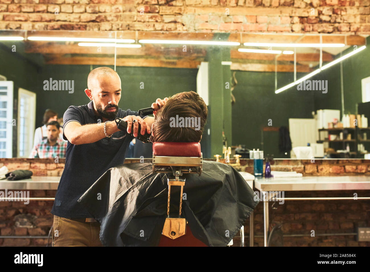 Male barber giving customer a haircut in barbershop Stock Photo