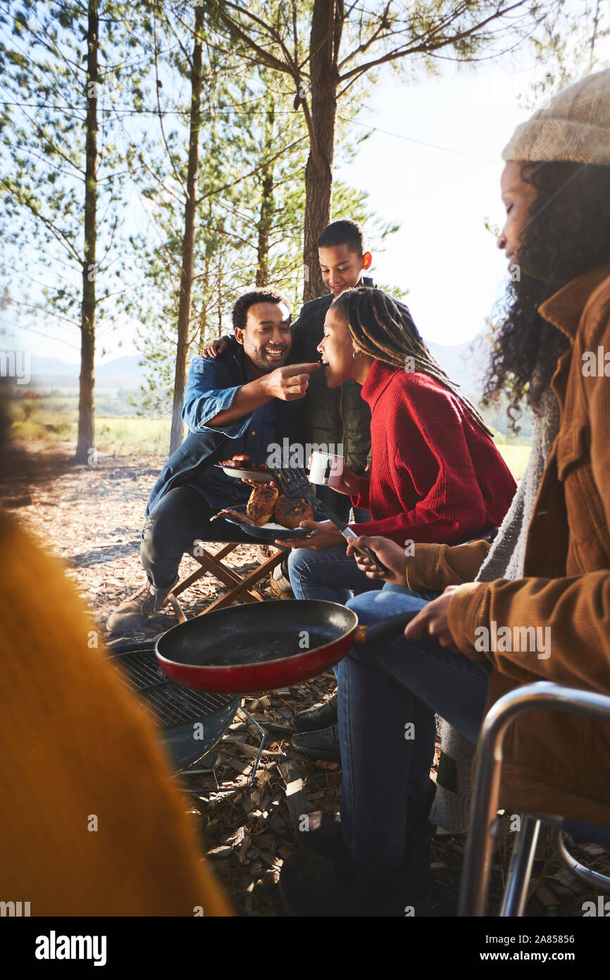 Husband feeding wife at campsite Stock Photo