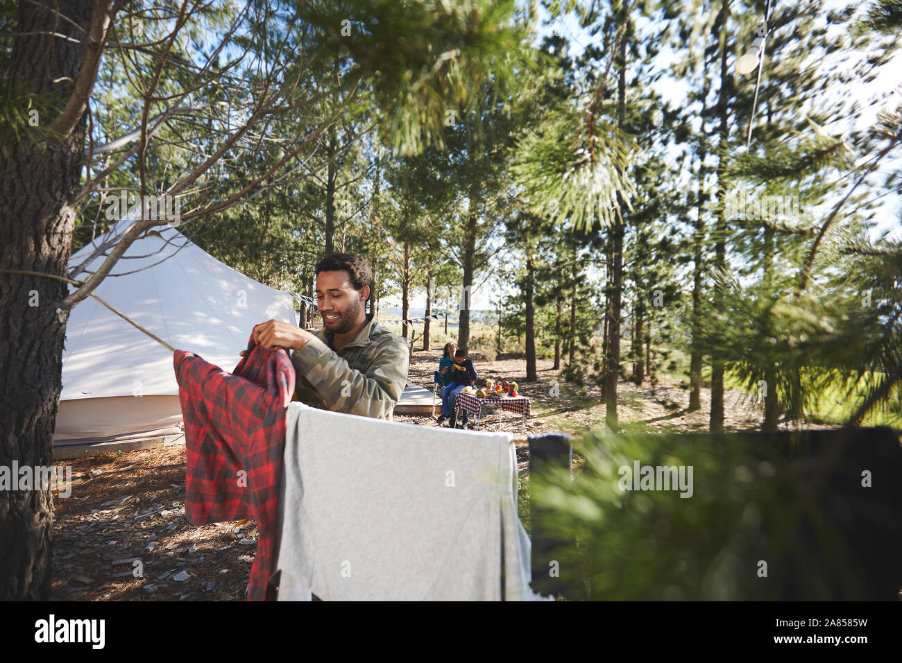 Man hanging laundry on clothesline at campsite in woods Stock Photo