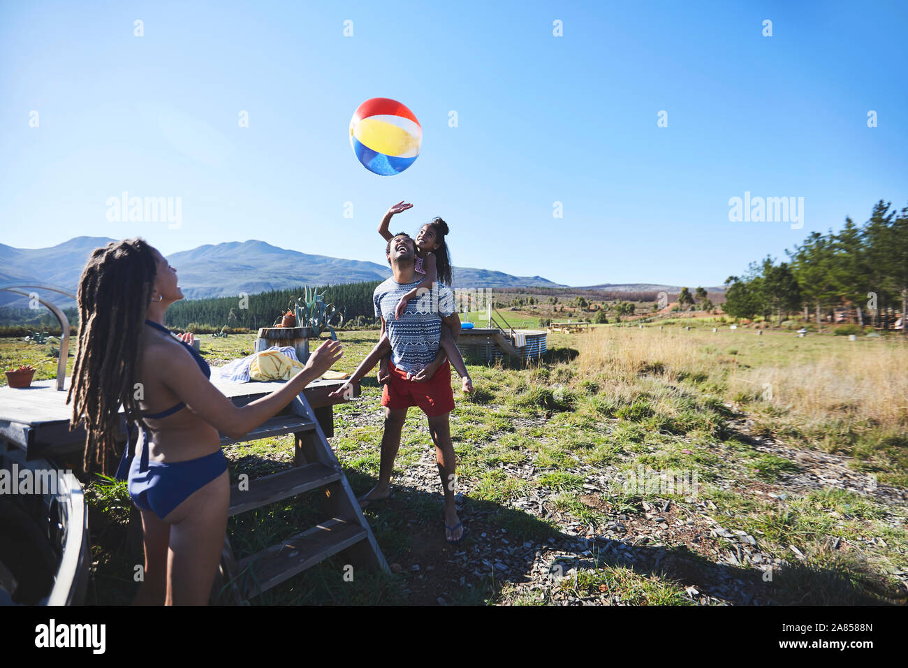 Happy, playful family with beach ball in sunny, summer field Stock Photo