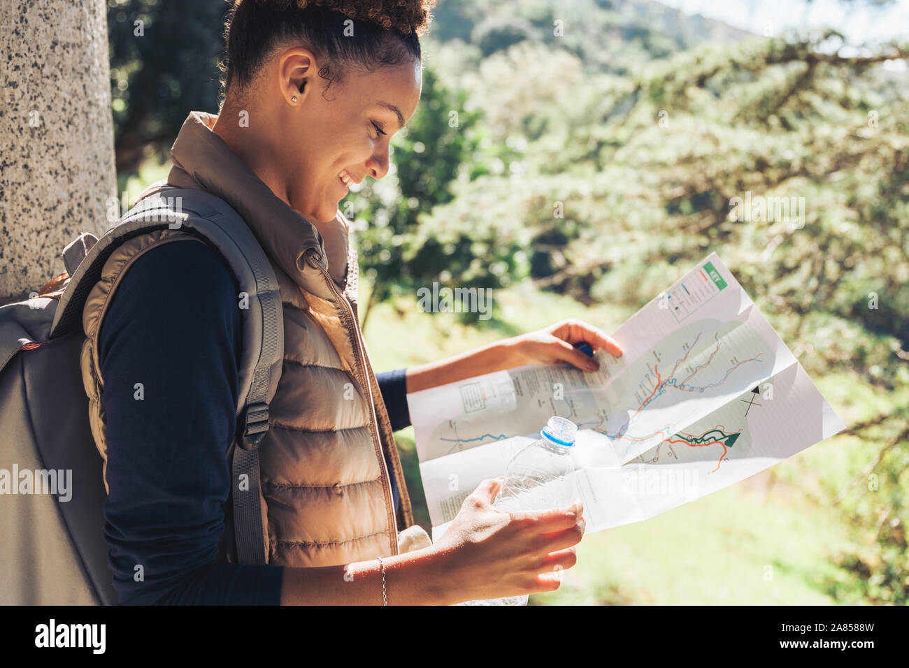 Young female hiker looking at trail map ins sunny woods Stock Photo
