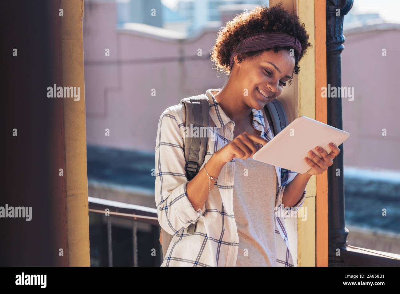 Young woman using digital tablet on sunny balcony Stock Photo