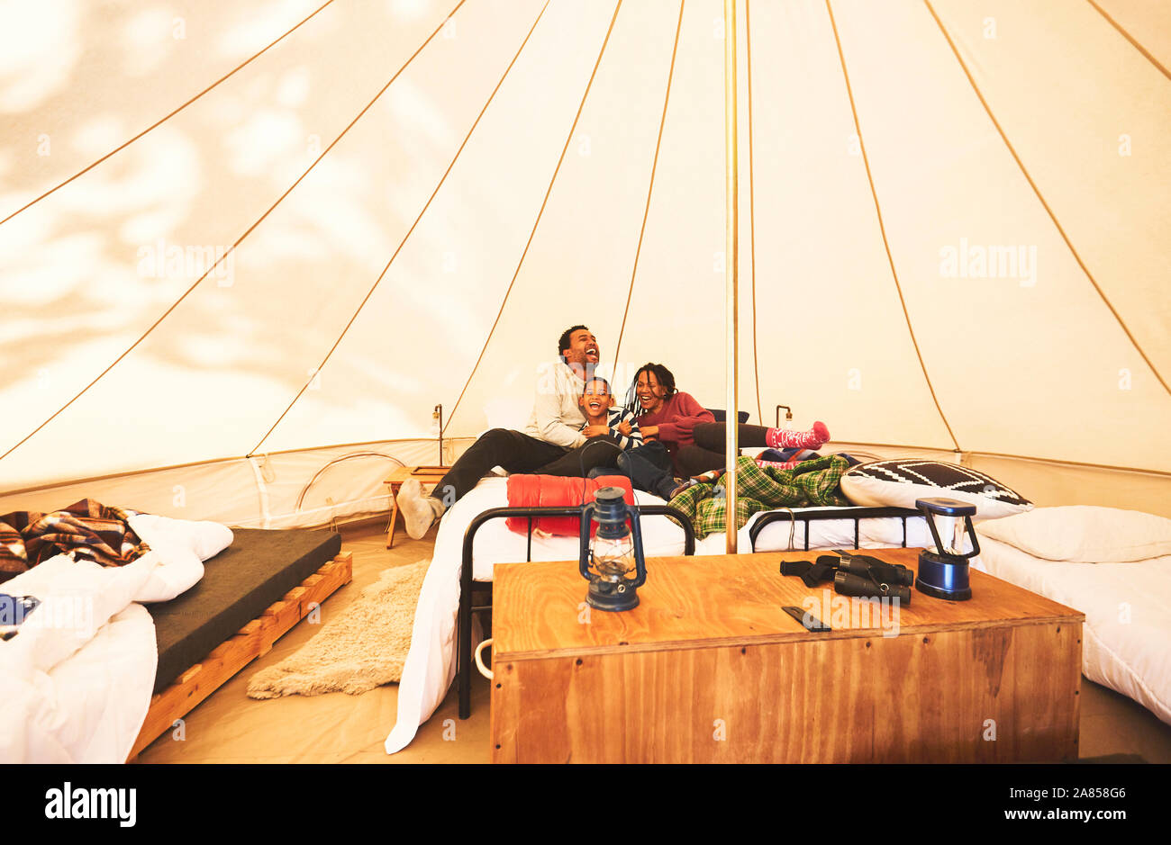 Happy, carefree family relaxing on bed in camping yurt Stock Photo