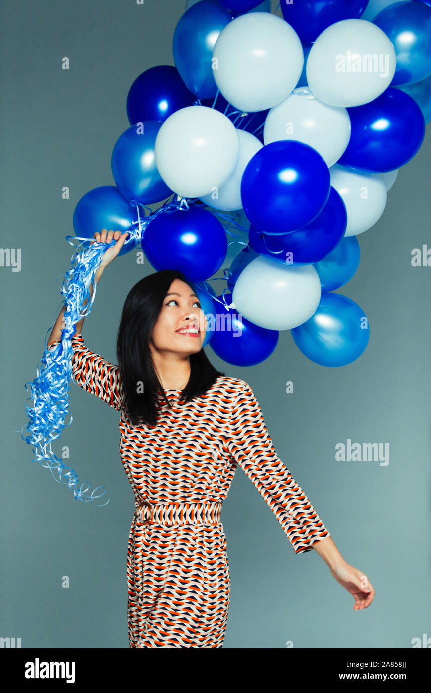 Smiling, carefree woman with blue and white balloon bunch Stock Photo