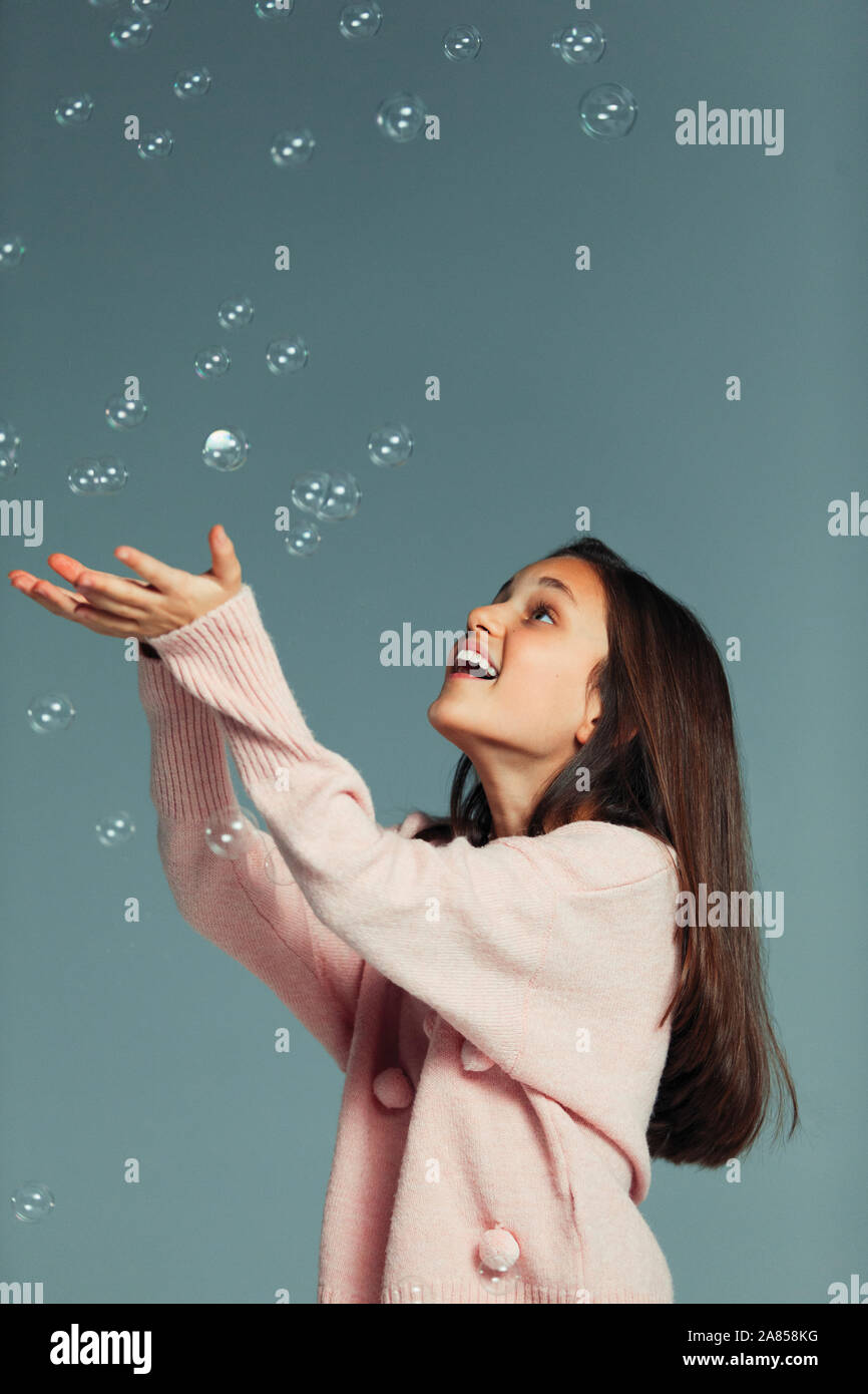 Playful, carefree girl catching falling bubbles Stock Photo