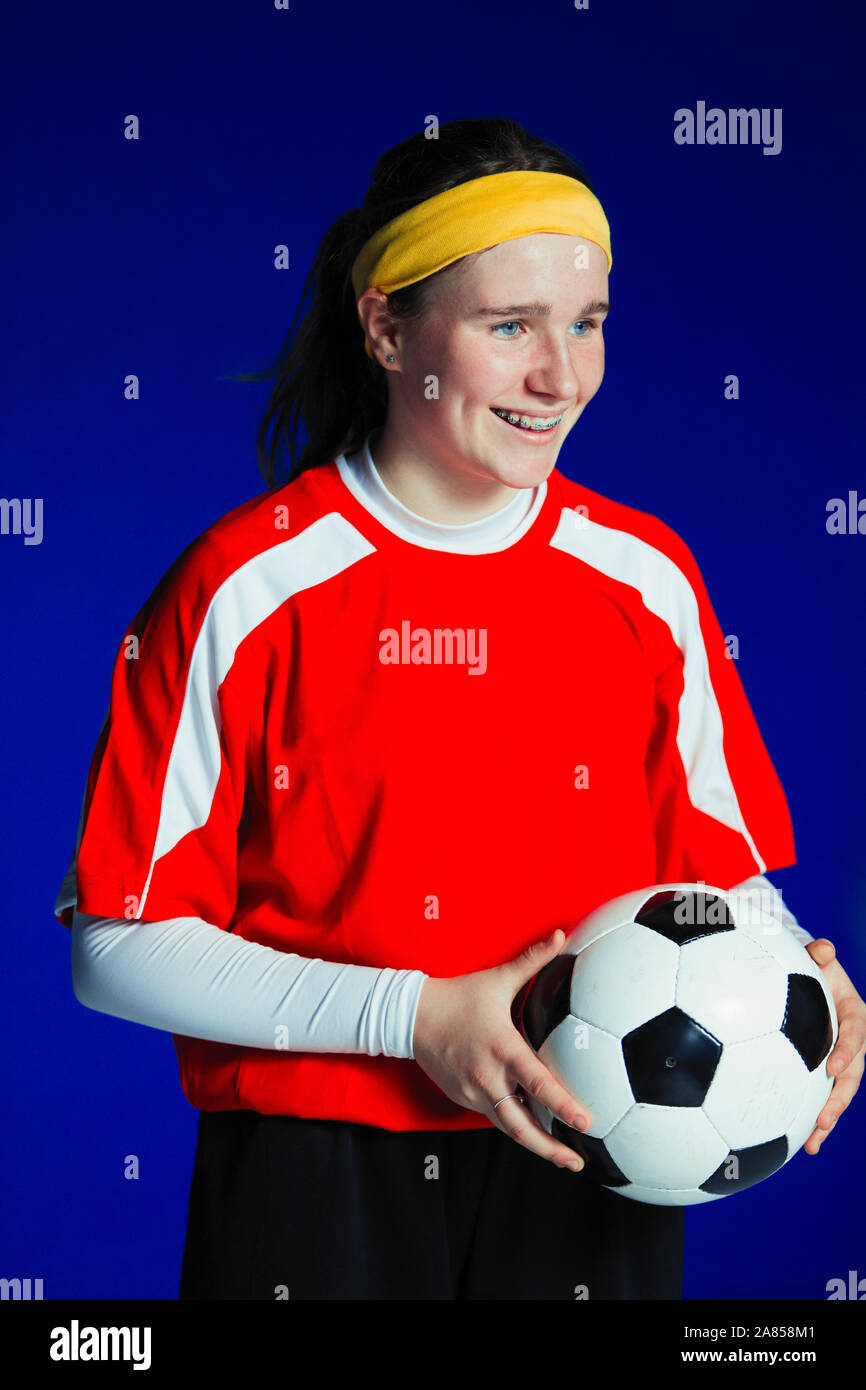 Portrait smiling teenage girl soccer player holding ball Stock Photo