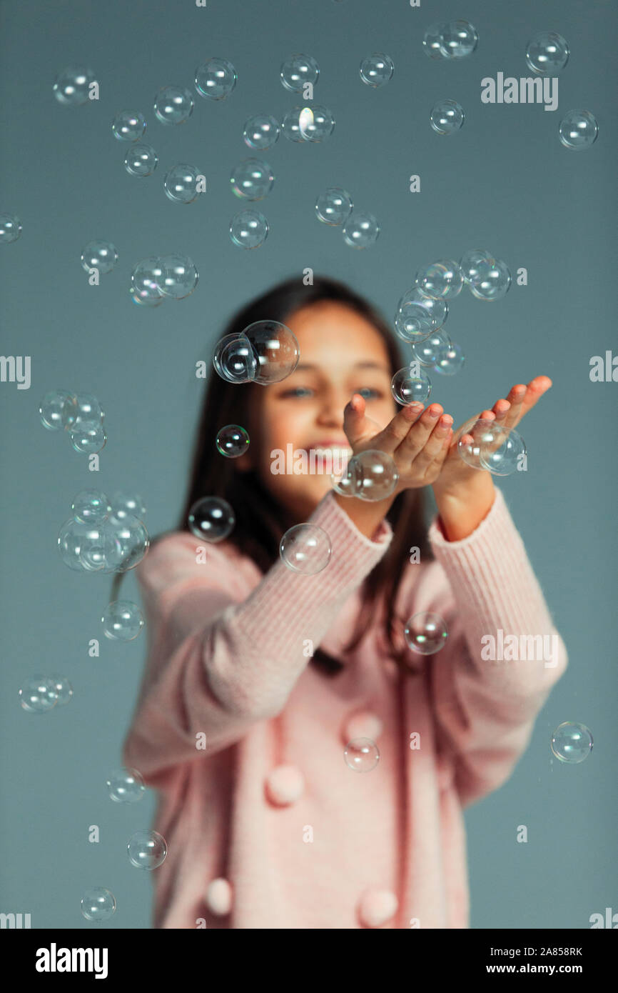 Happy, playful girl catching falling bubbles Stock Photo