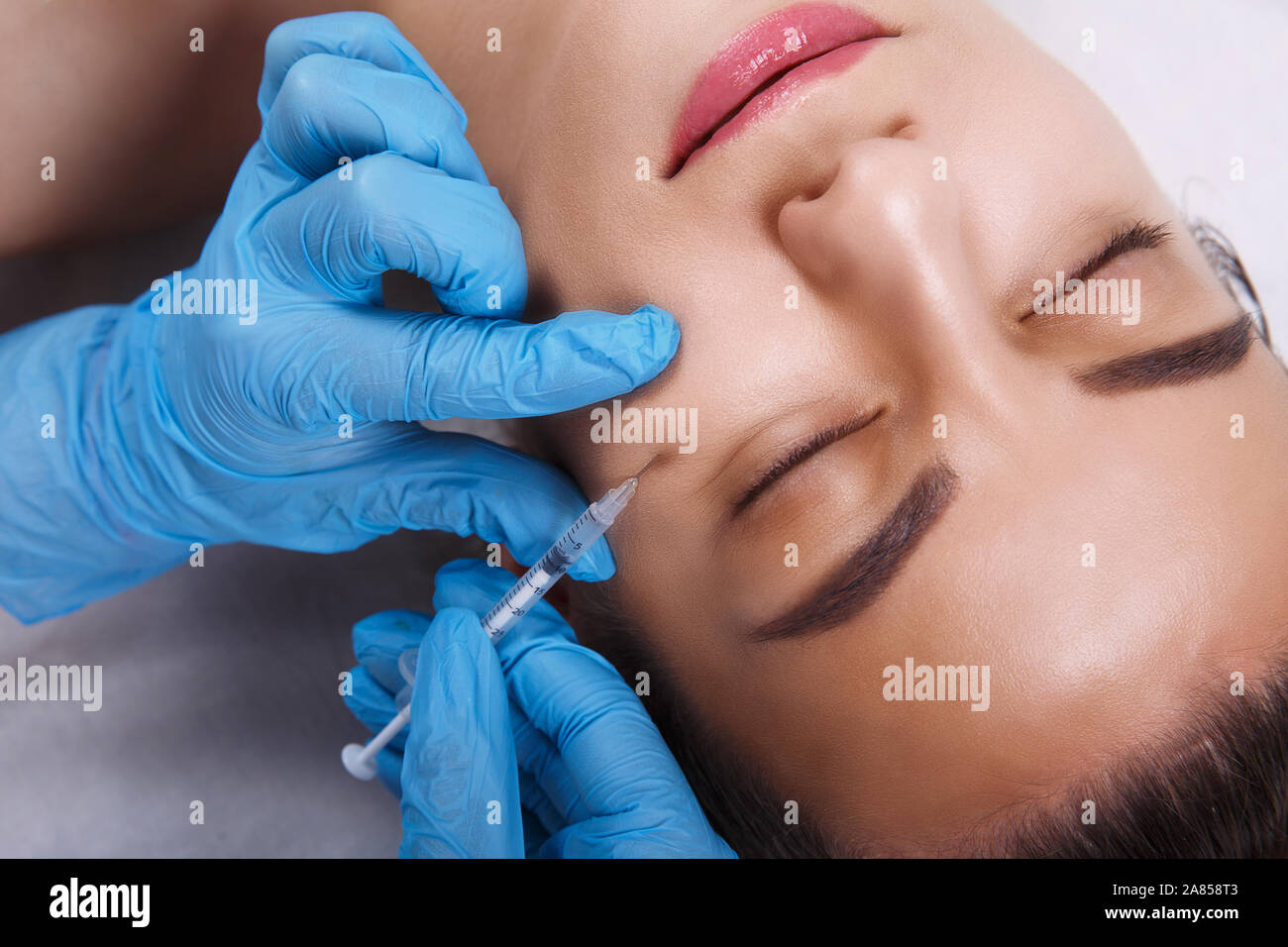 Facial Beauty Injections. Portrait Beautiful Young Woman Receiving Hyaluronic Acid Injection. Closeup Of Hands In Gloves Holding Syringe Near Stock Photo