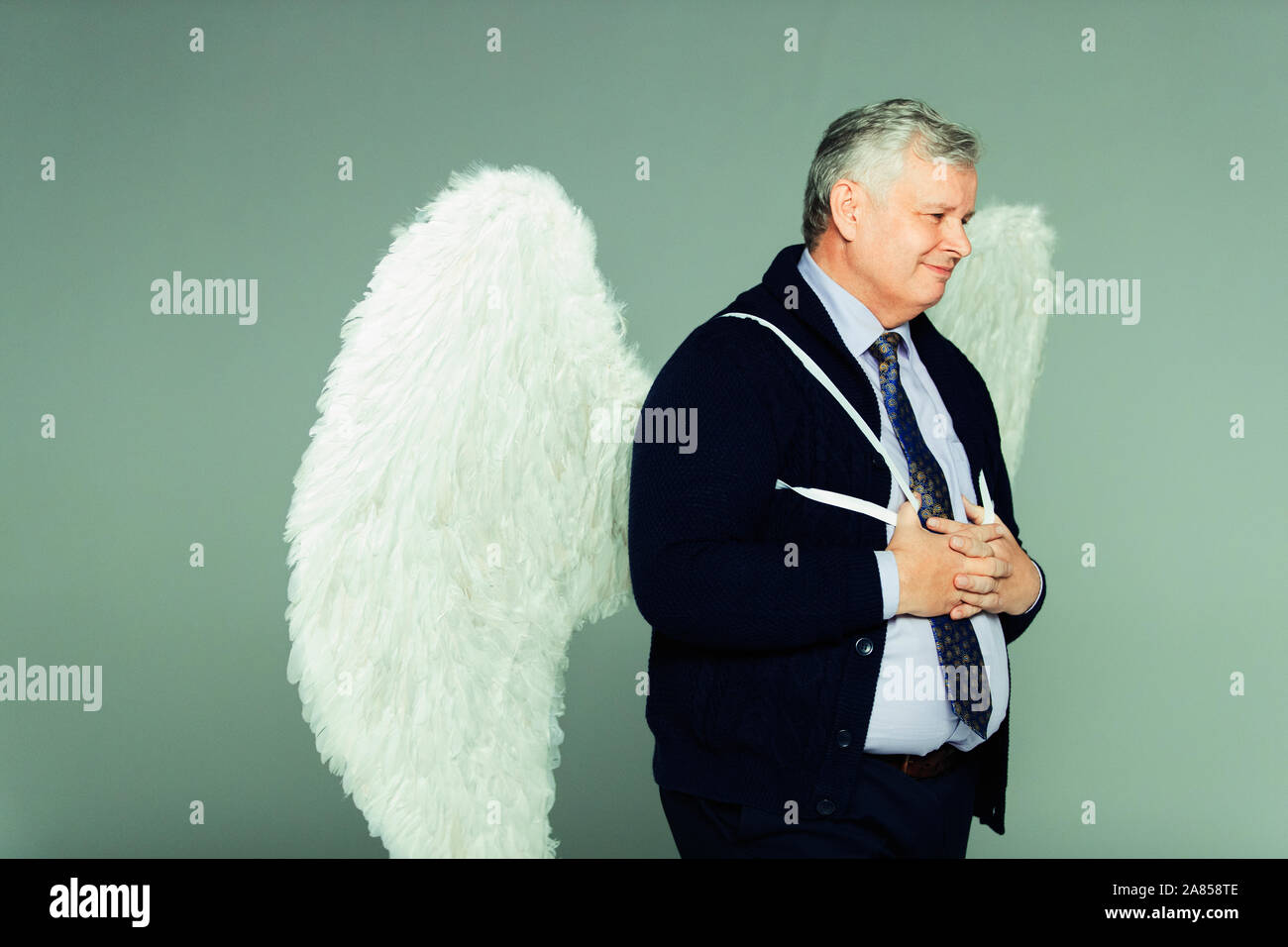 Smiling businessman wearing angel wings Stock Photo