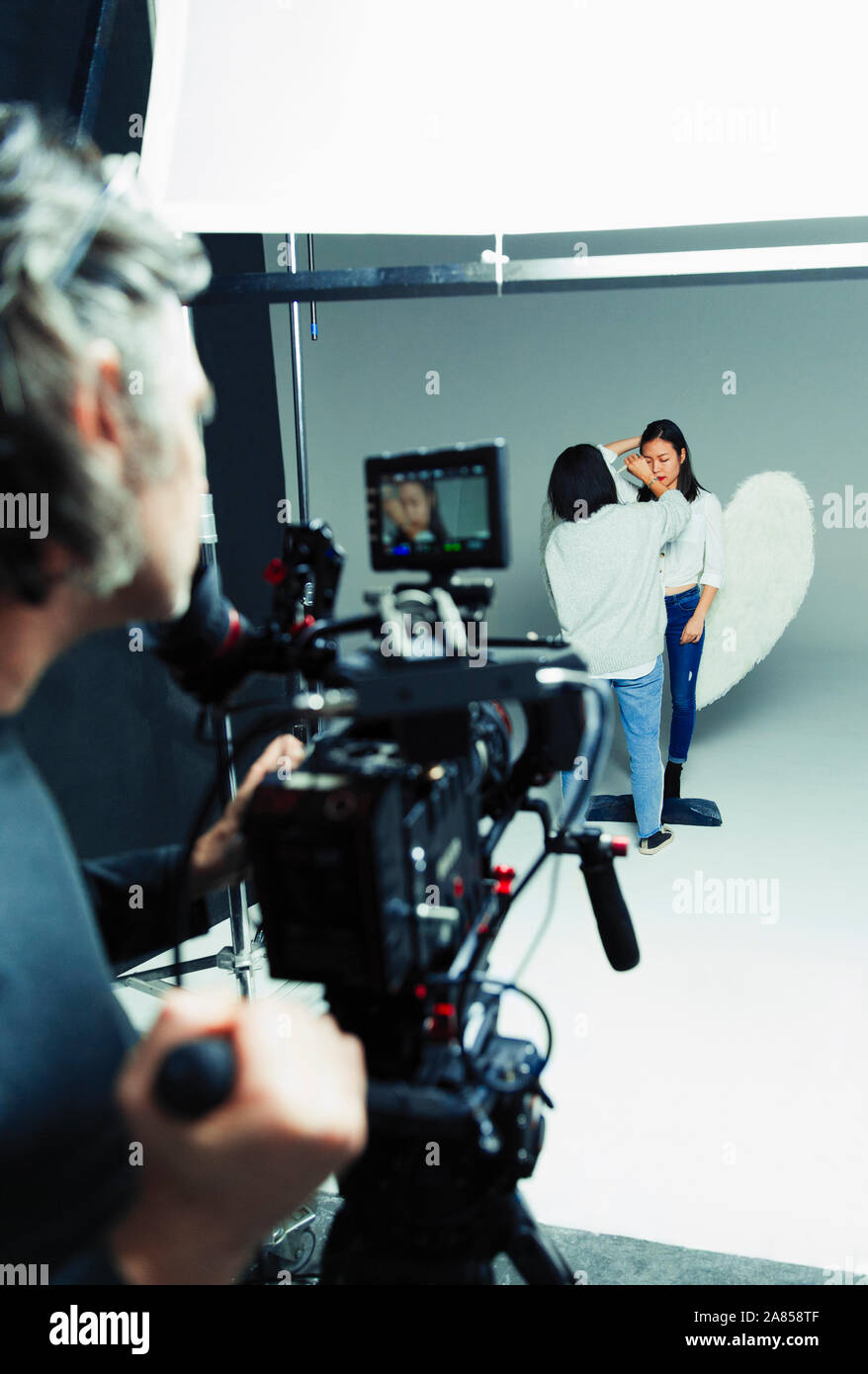 Photographer waiting for makeup artist and model in angel wings during ...