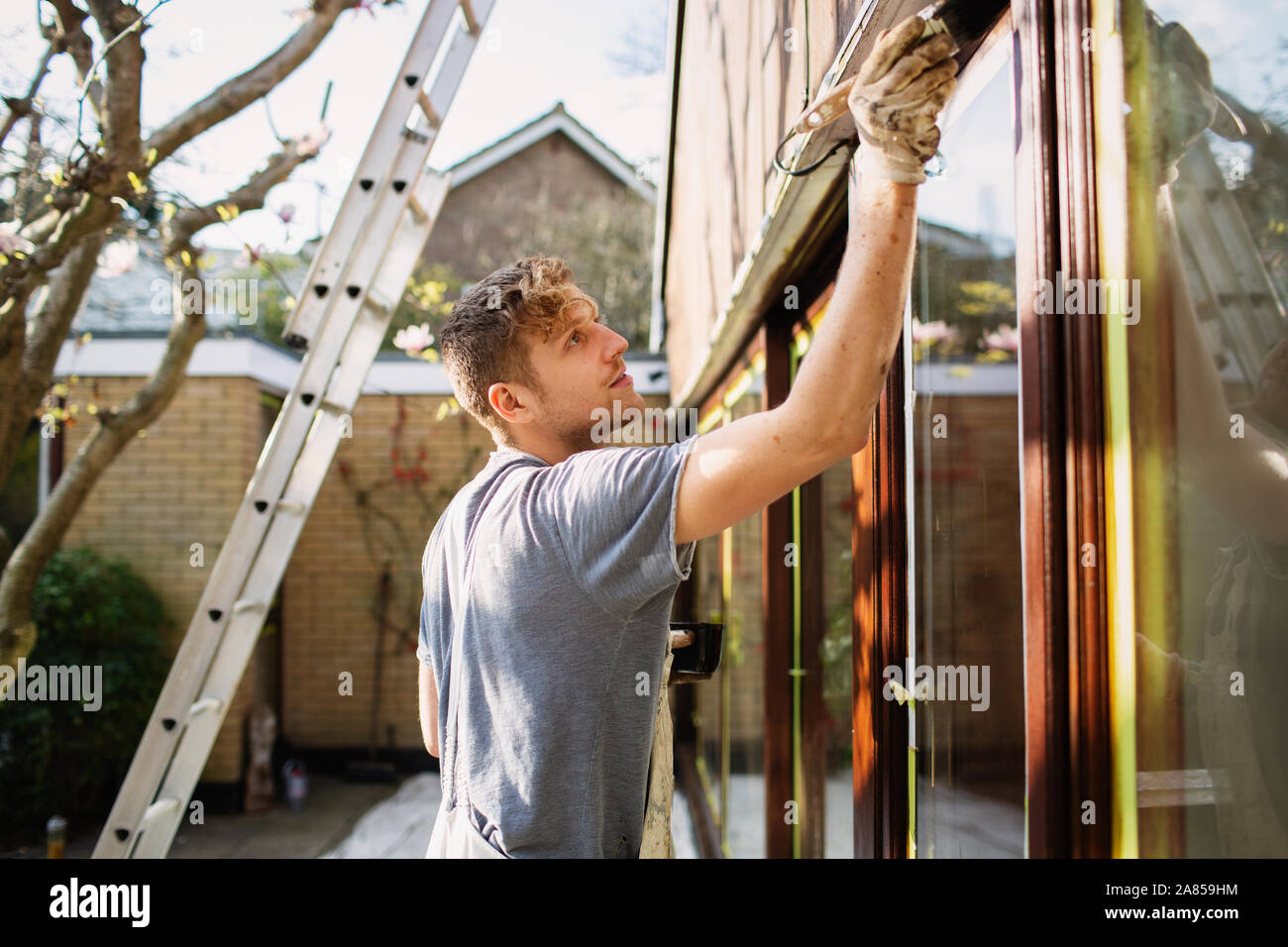 Male painter painting home exterior window trim Stock Photo