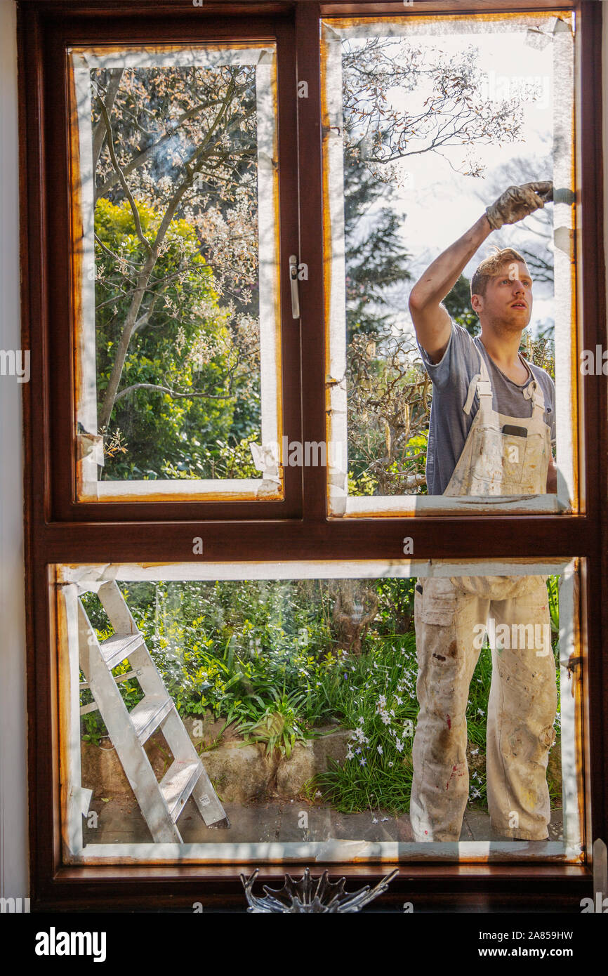 Male painter painting home exterior window trim Stock Photo