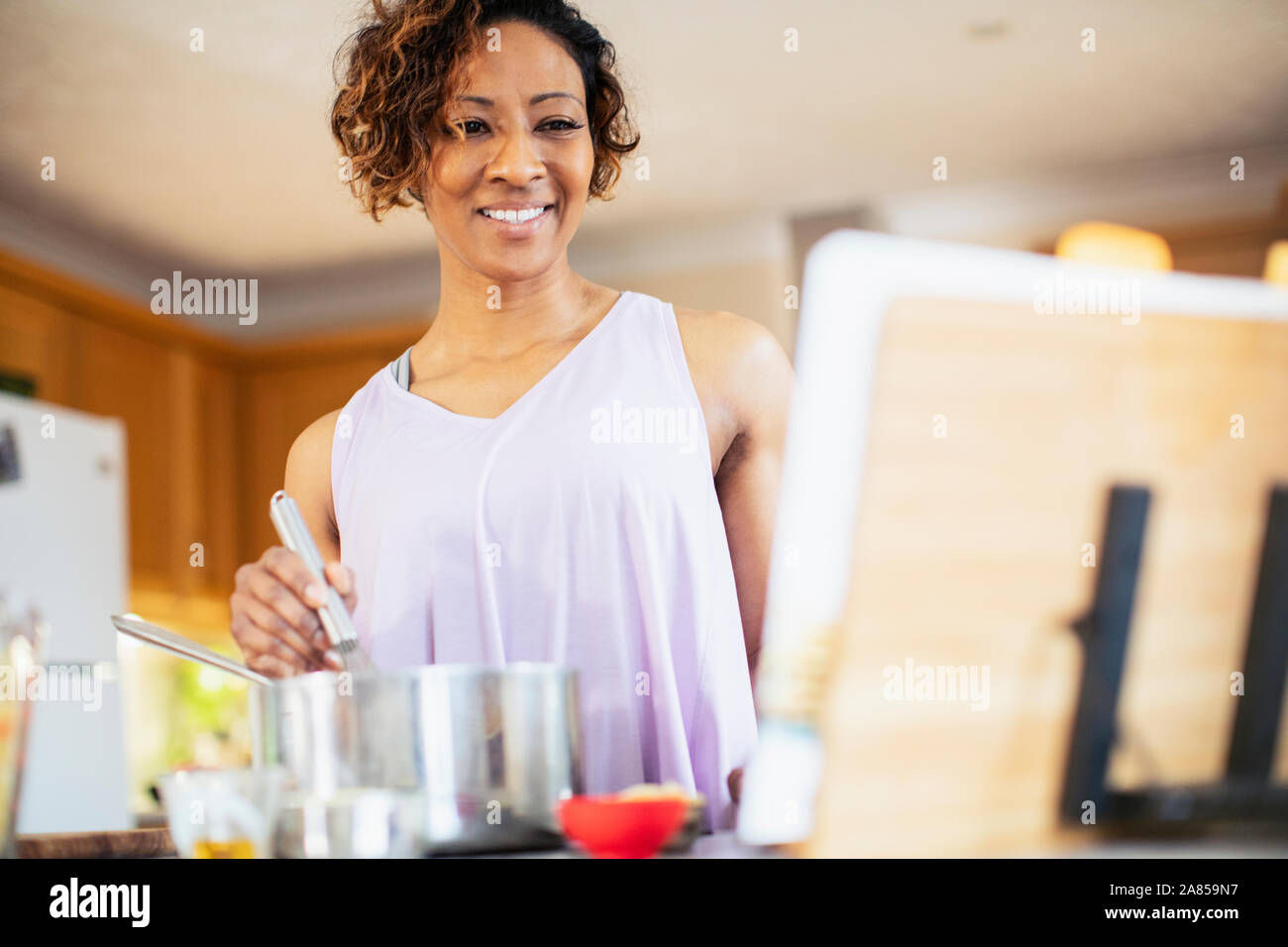 Smiling woman with cookbook cooking in kitchen Stock Photo