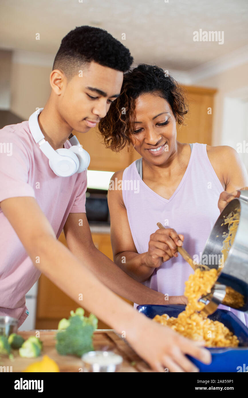Mother and teenage son cooking in kitchen Stock Photo