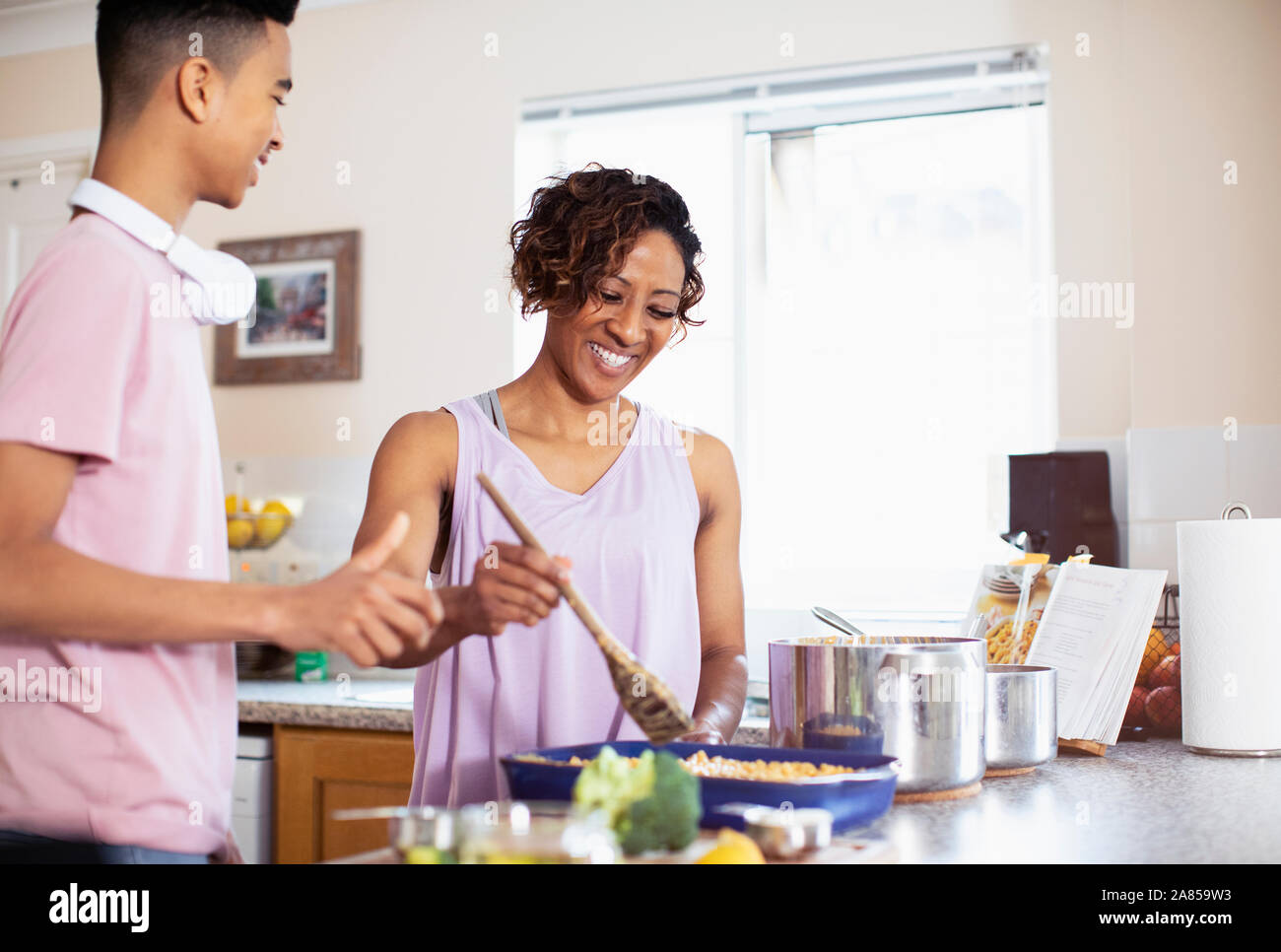 Mother and teenage son cooking in kitchen Stock Photo