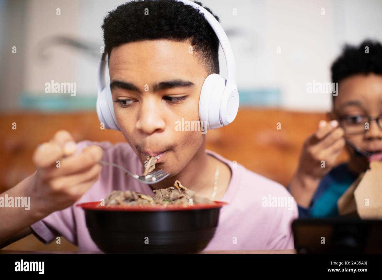 Teenage boy with headphones eating Stock Photo