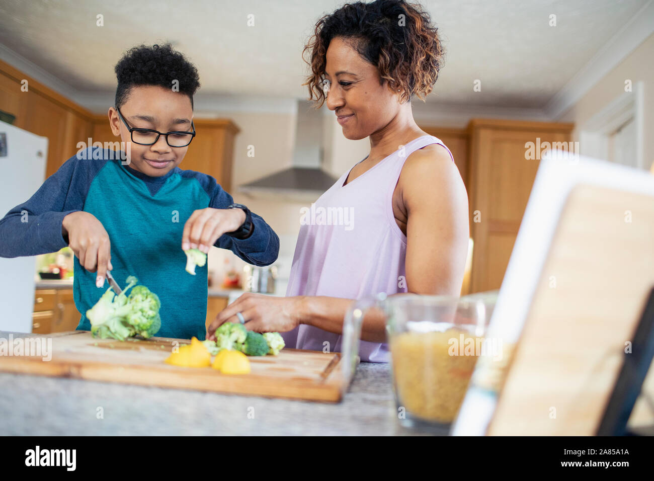 Mother and son cooking, cutting vegetables in kitchen Stock Photo