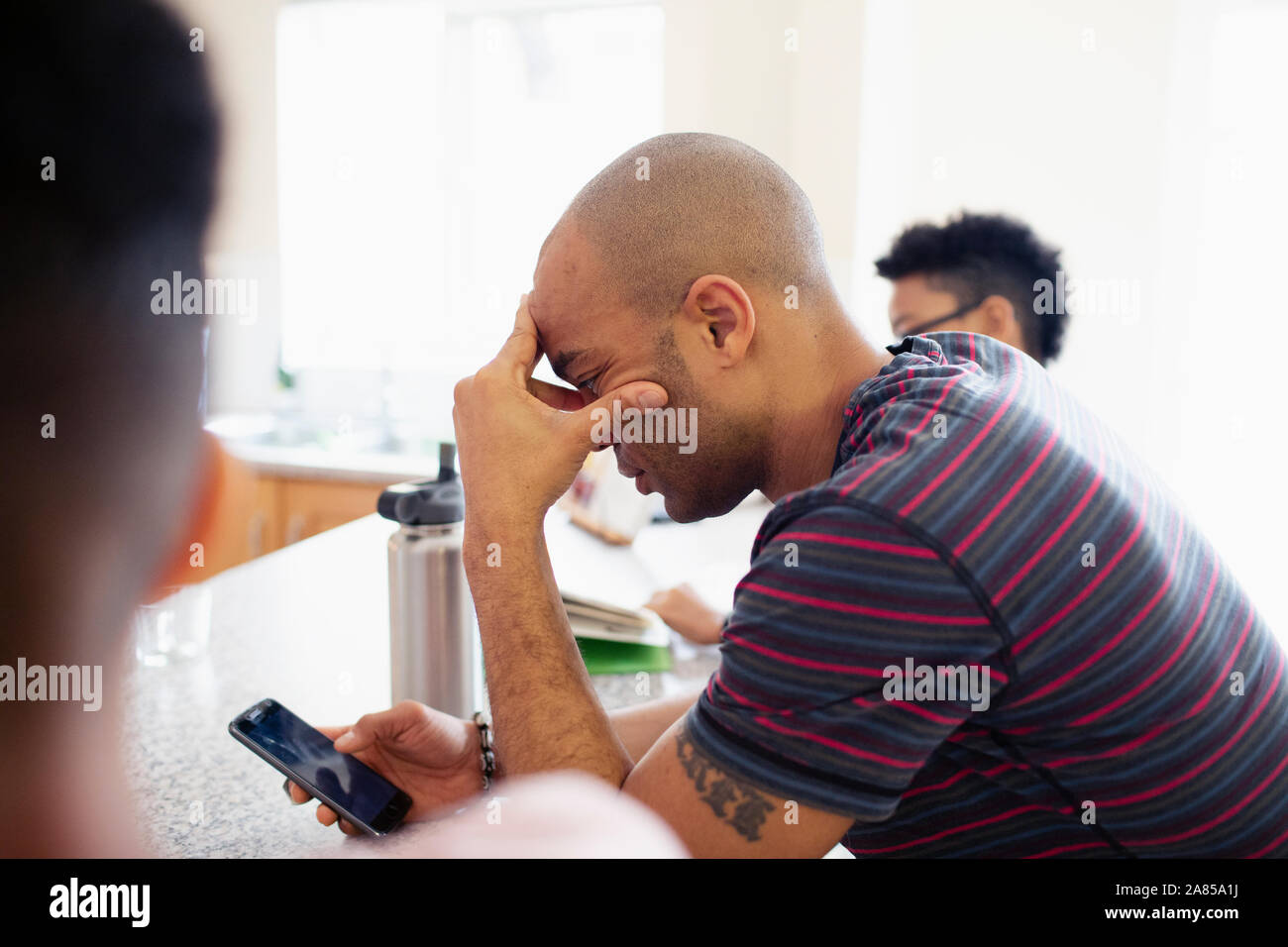 Man with head in hands using smart phone Stock Photo
