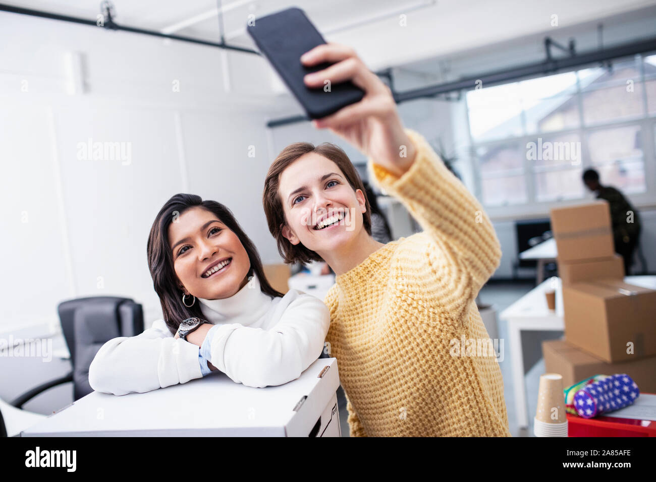 Smiling businesswomen taking selfie in new office Stock Photo