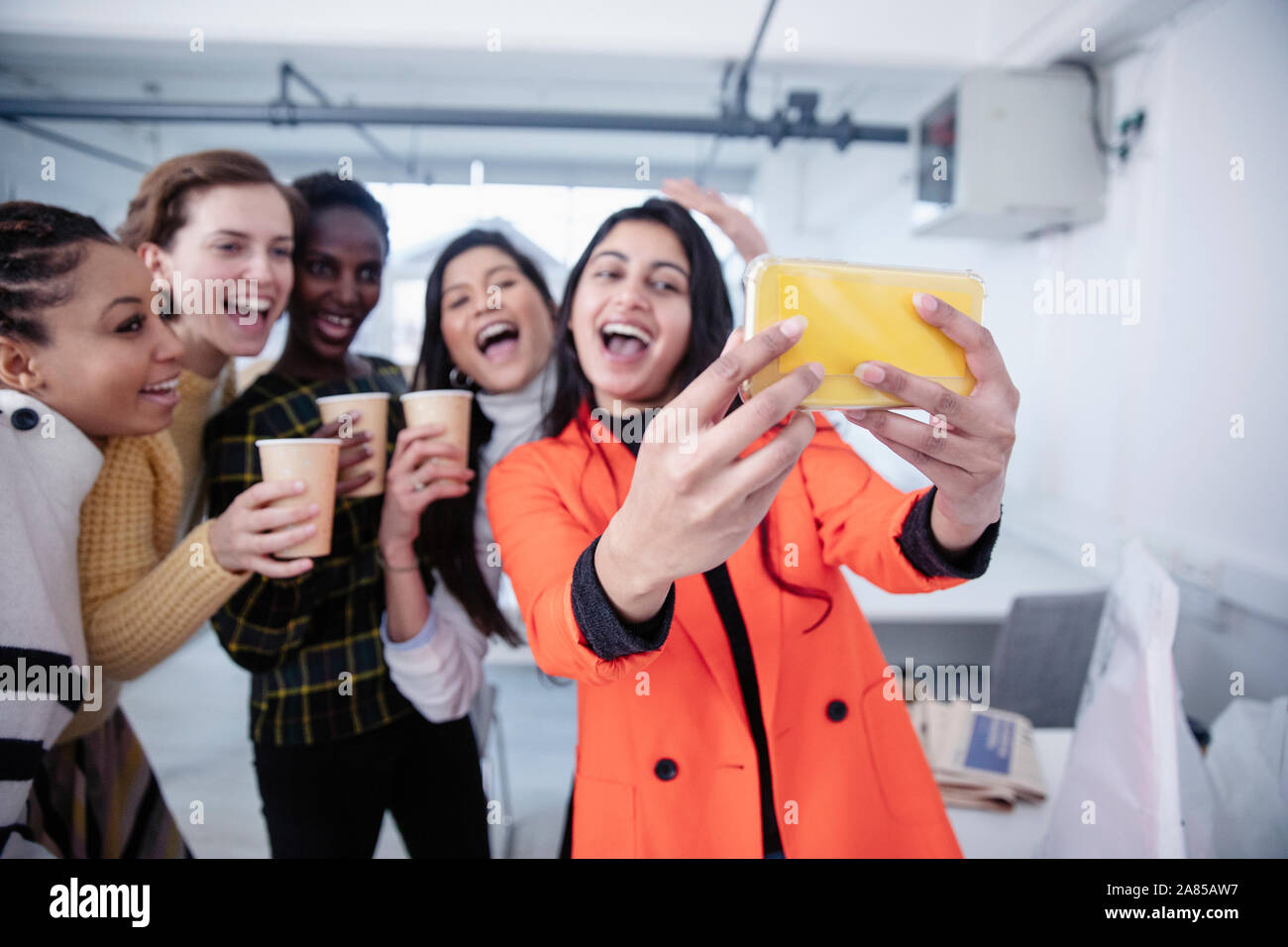 Happy businesswomen celebrating, taking selfie in office Stock Photo