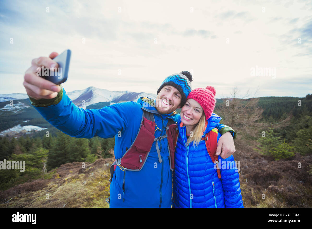 Happy couple hiking, taking selfie on mountaintop Stock Photo