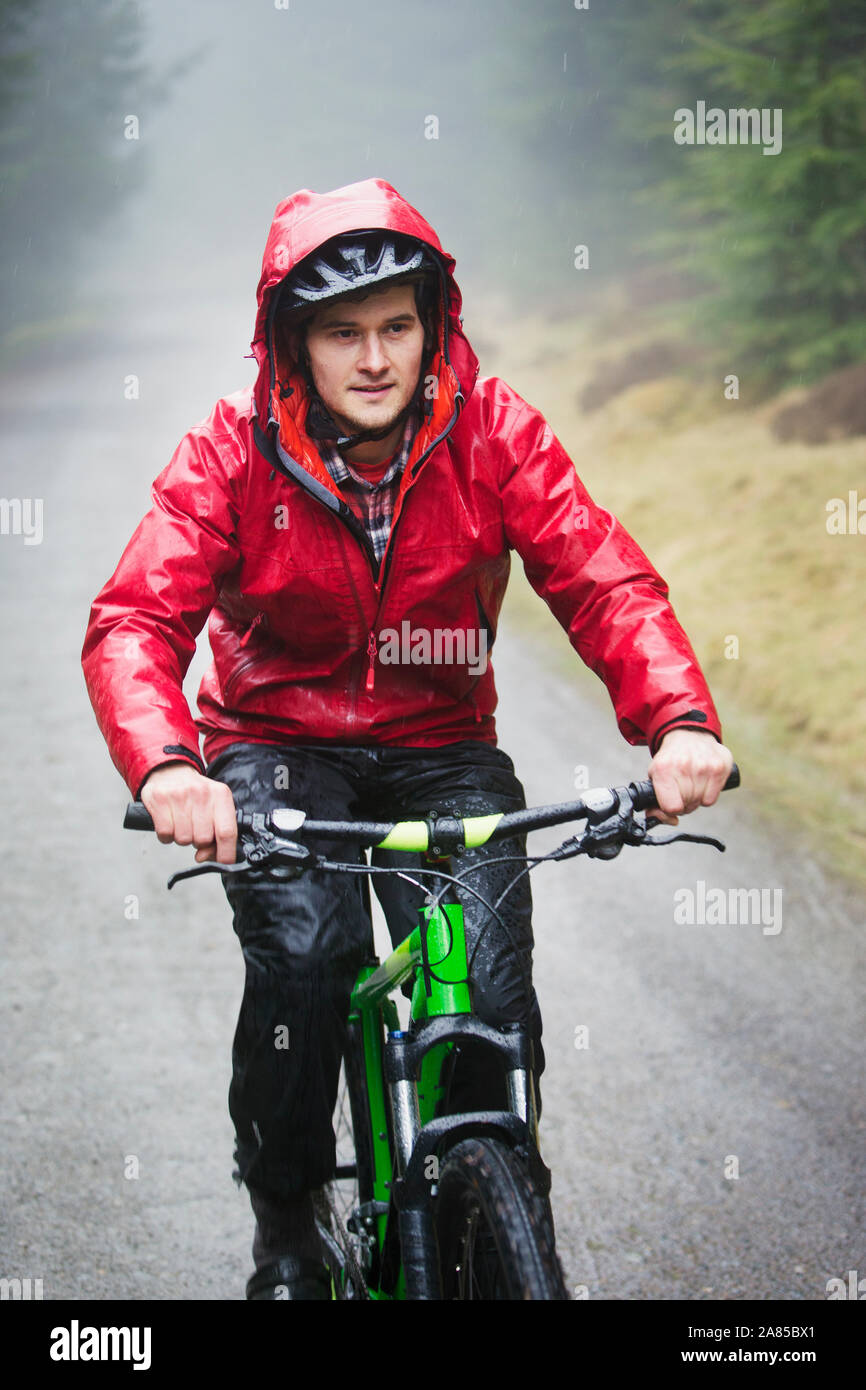Man in rain jacket mountain biking on trail Stock Photo Alamy