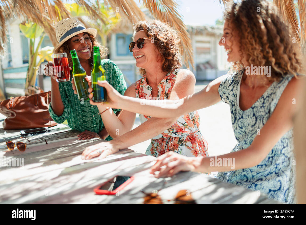 Happy women friends drinking cocktail and beer at sunny beach bar Stock Photo