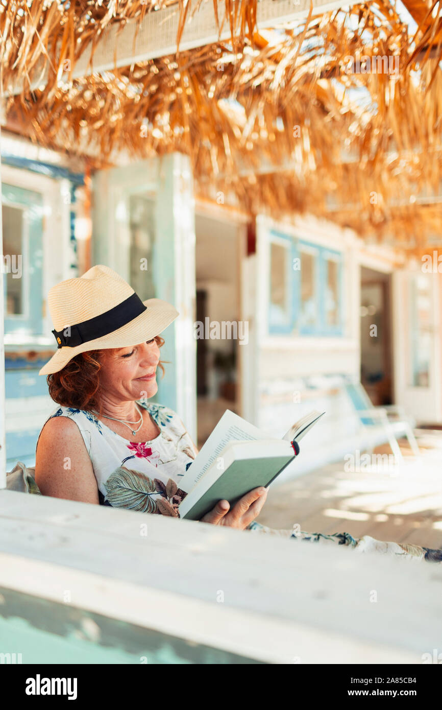 Woman reading book on beach hut patio Stock Photo - Alamy